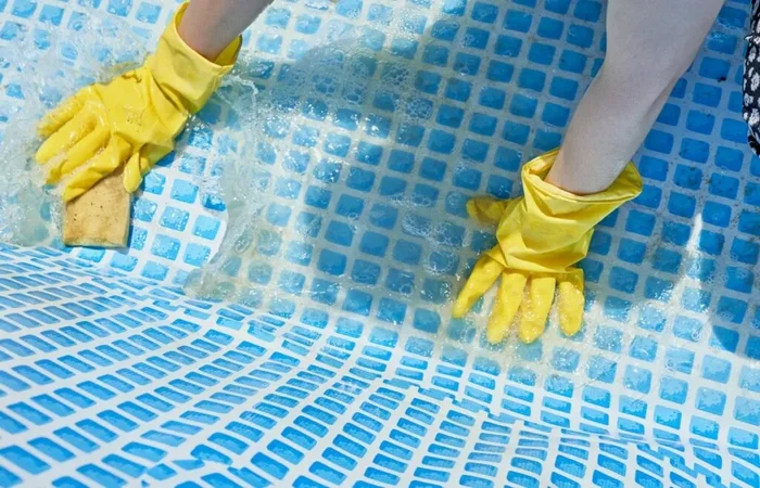 un homme en plein travaux de nettoyage de sol d'une piscine